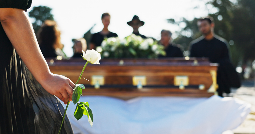 woman holding a white rose during a funeral - Marietta wrongful death lawyer