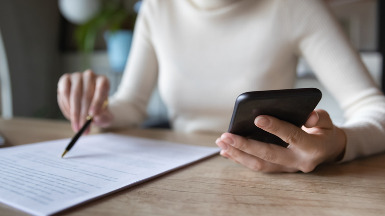 woman on her phone while reading a document - how to choose a personal injury lawyer